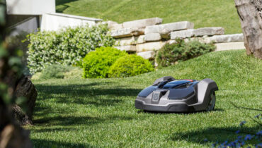 A Husqvarna robotic mower on a green lawn