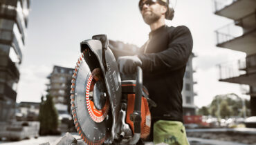 A builder standing behind one of his construction tools - a Husqvarna power cutter.