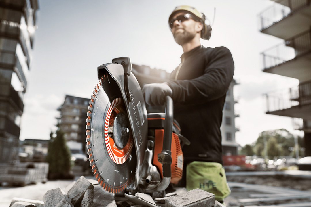 A builder standing behind one of his construction tools - a Husqvarna power cutter.