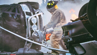 A fireman using a Husqvarna rescue saw to cut steel at the scene of a car accident.