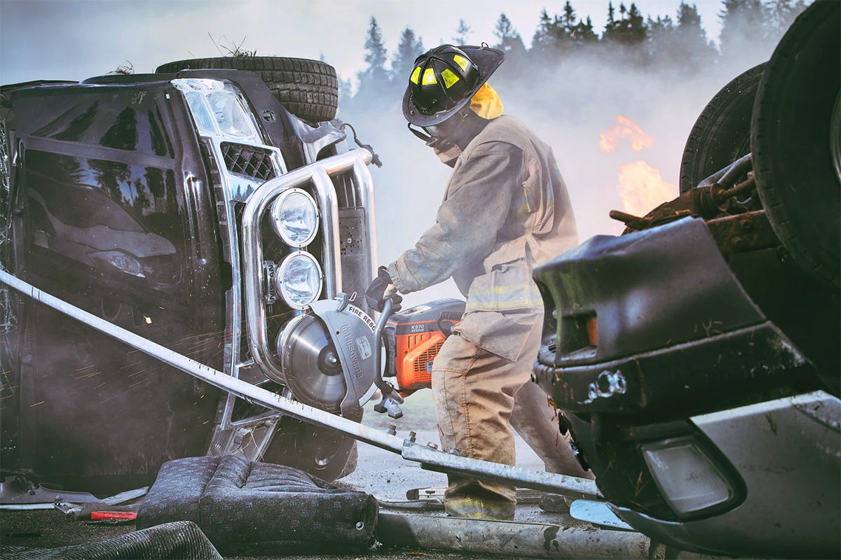 A fireman using a Husqvarna rescue saw to cut steel at the scene of a car accident.