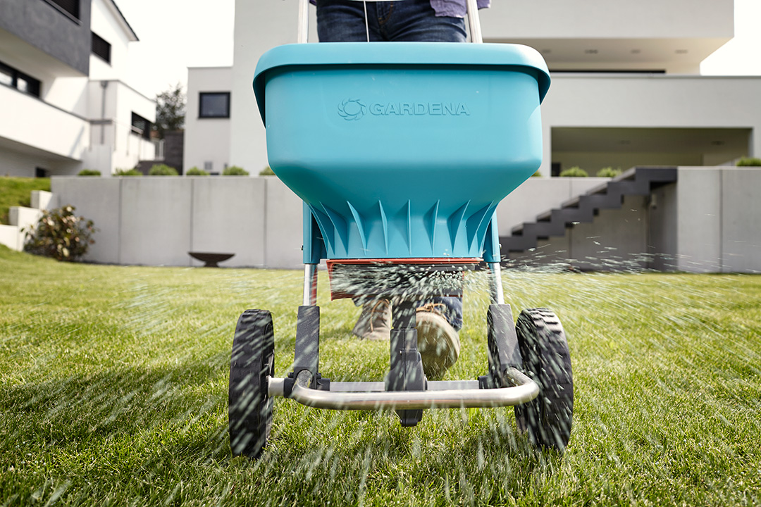 A GARDENA spreader XL being used to disperse fertiliser on a healthy, green lawn.