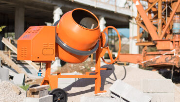 An orange SIRL concrete mixer on the sit of a construction project.
