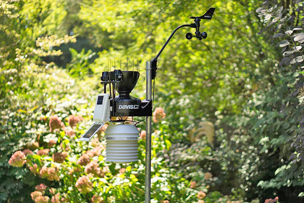 A Davis weather station in a lush green garden.