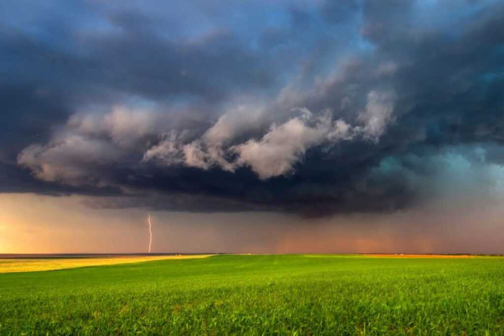 Dark clouds and a stormy sky over a green farm field.
