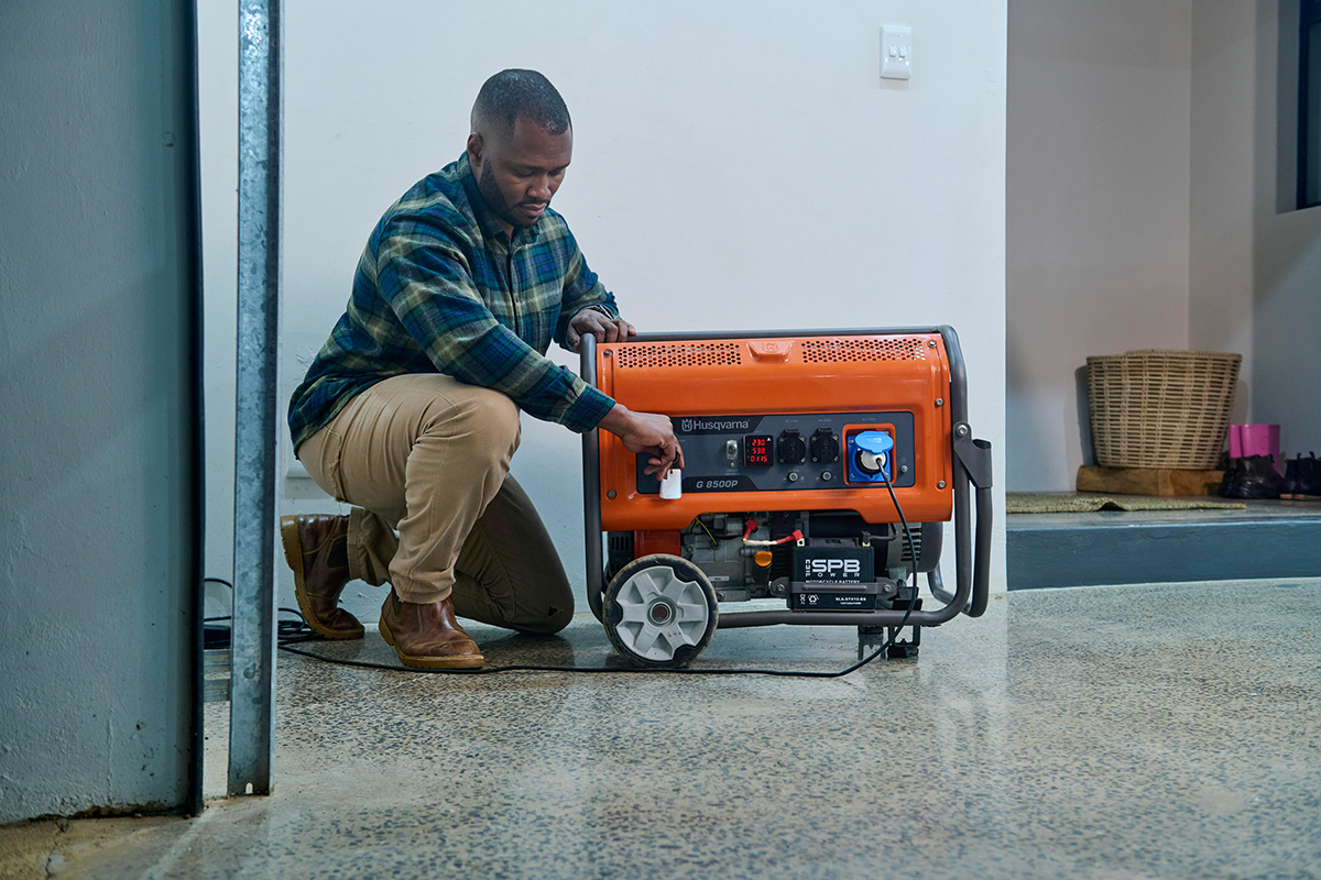 A man turning on his Husqvarna G8500P generator inside his garage.