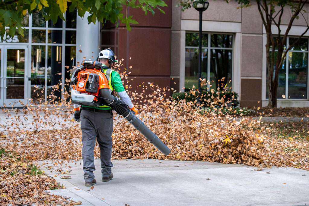 A man blowing leaves with a Husqvarna leaf blower